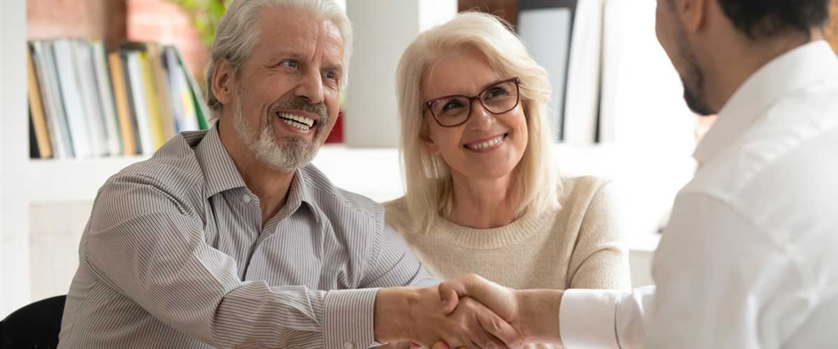 senior couple shakes hands with senior living professional