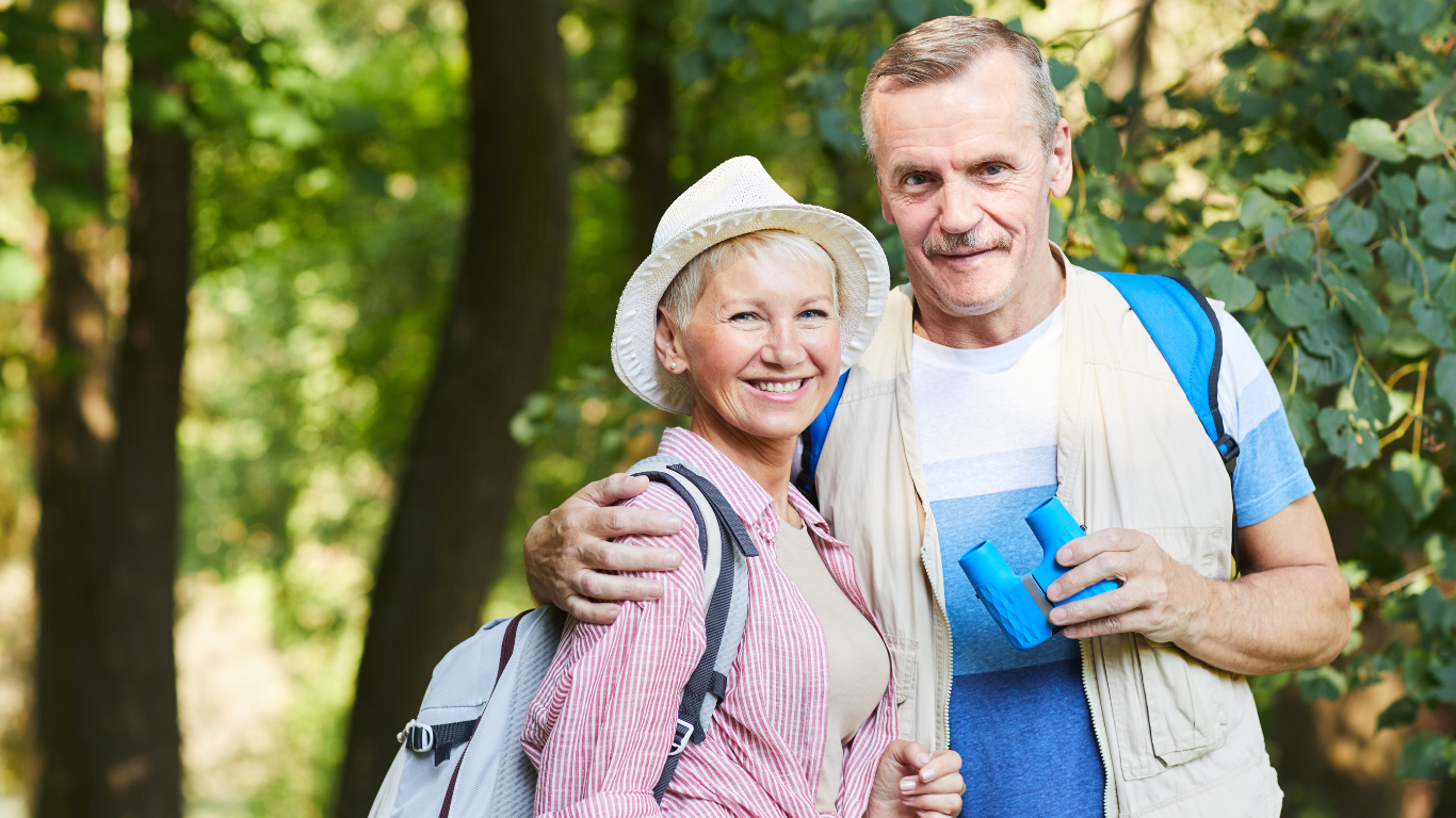 A senior couple posing while hiking in the woods