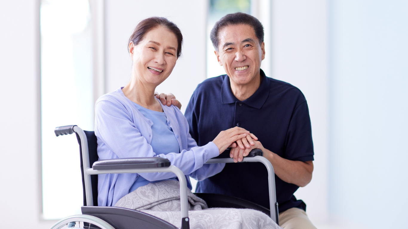 Blog Images (82) A man holding the hands of a woman in a wheelchair