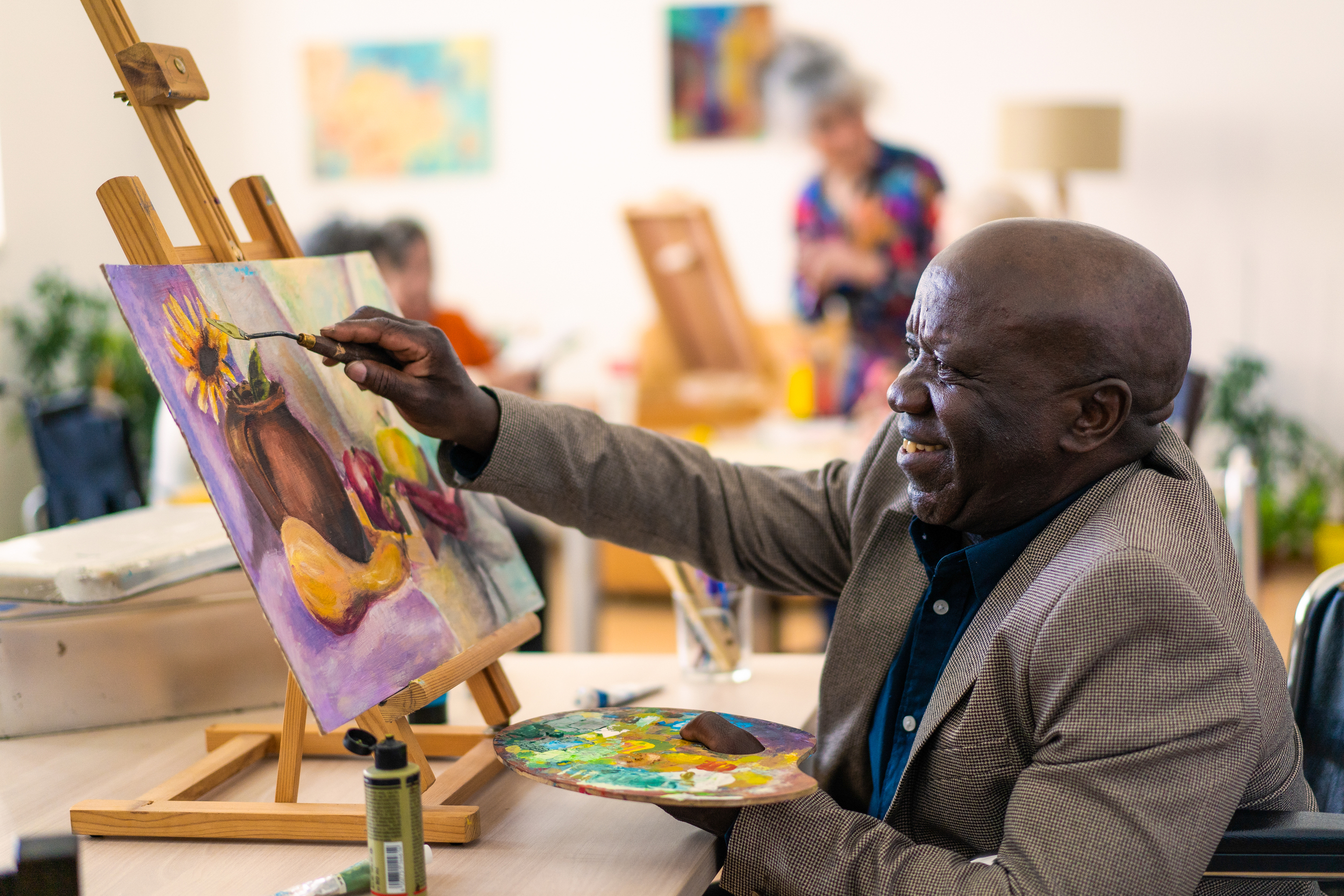 Smiling senior man painting a canvas of flowers