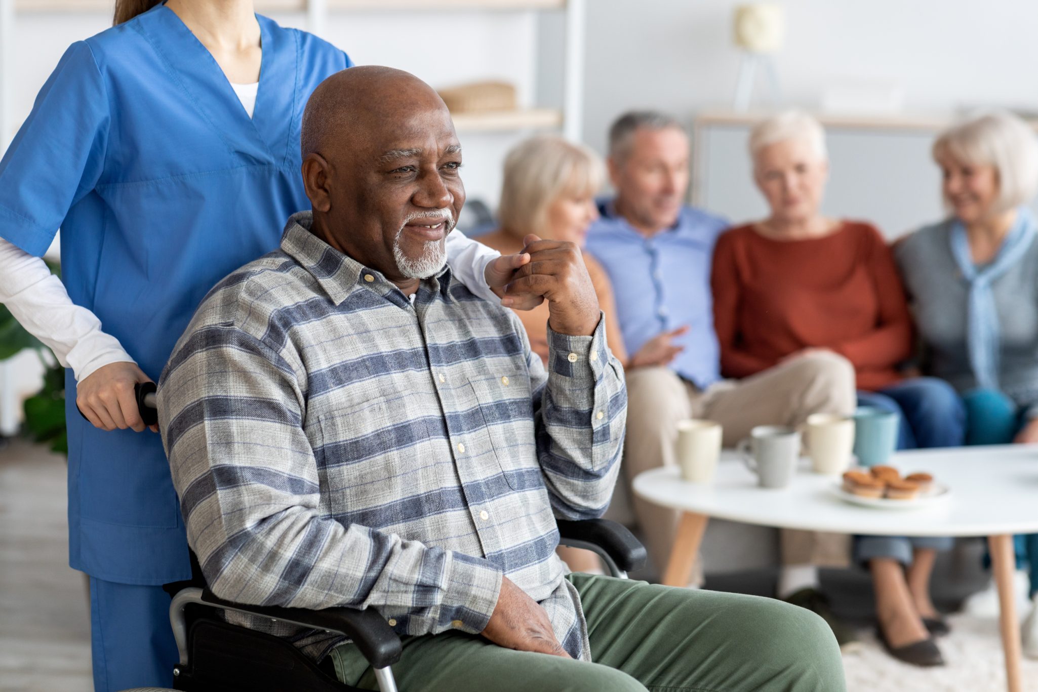 Senior man in wheelchair holding nurse hand