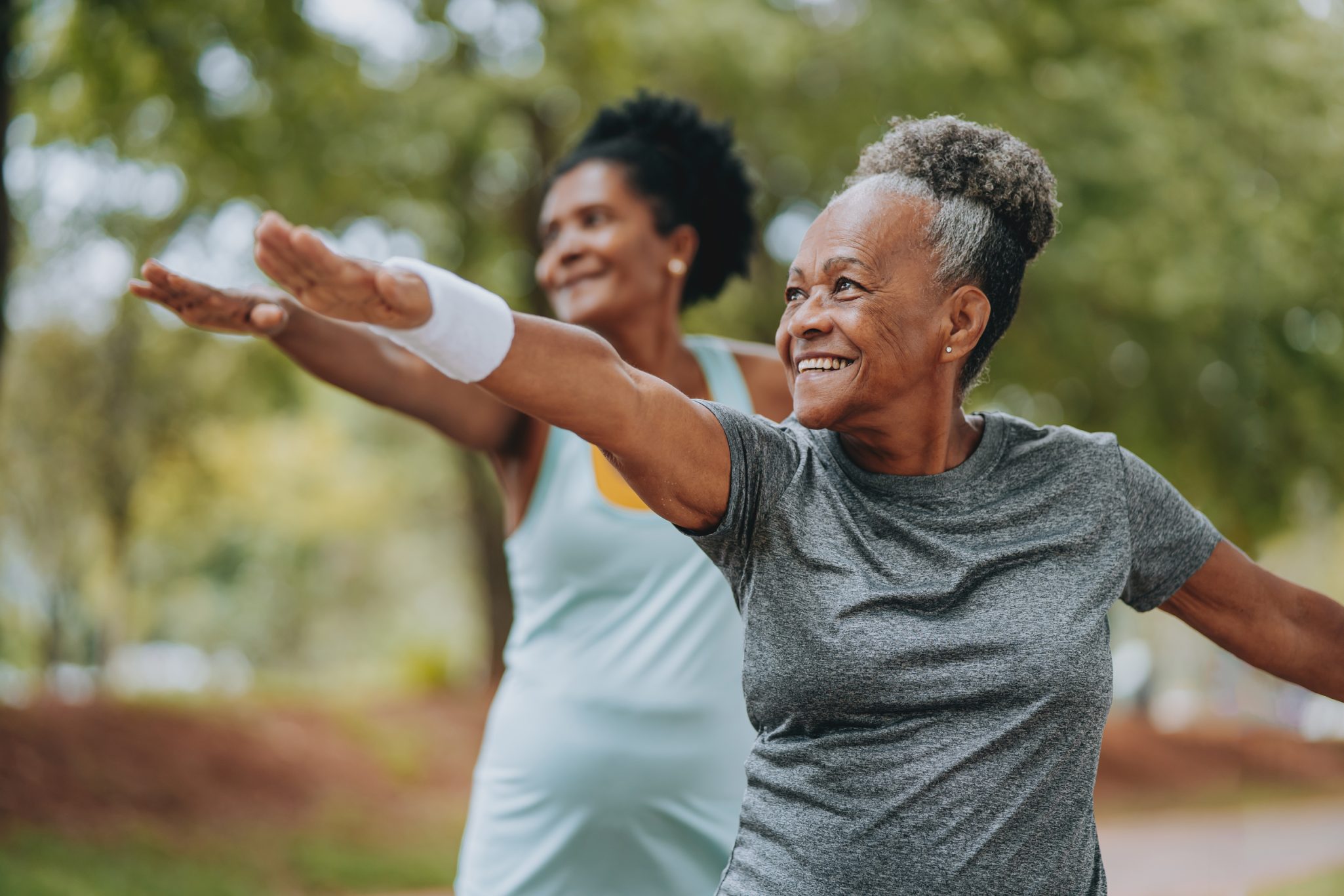 Two smiling senior woman doing yoga outdoors