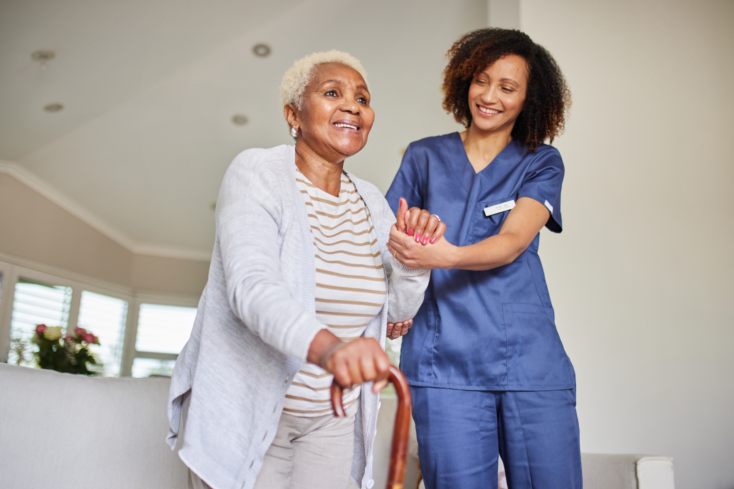 Female nurse assisting senior woman with cane