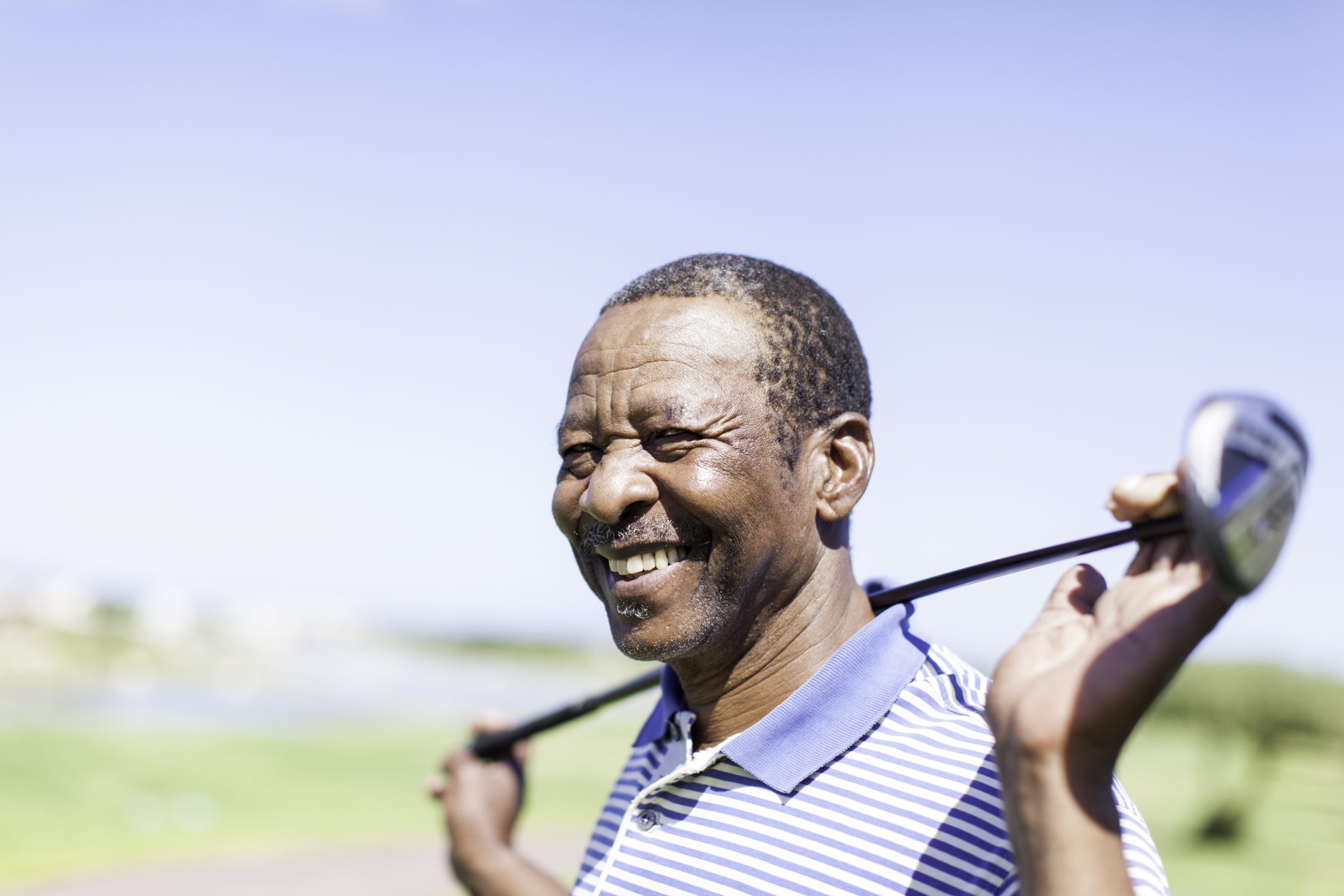 Senior male smiling holding golf club