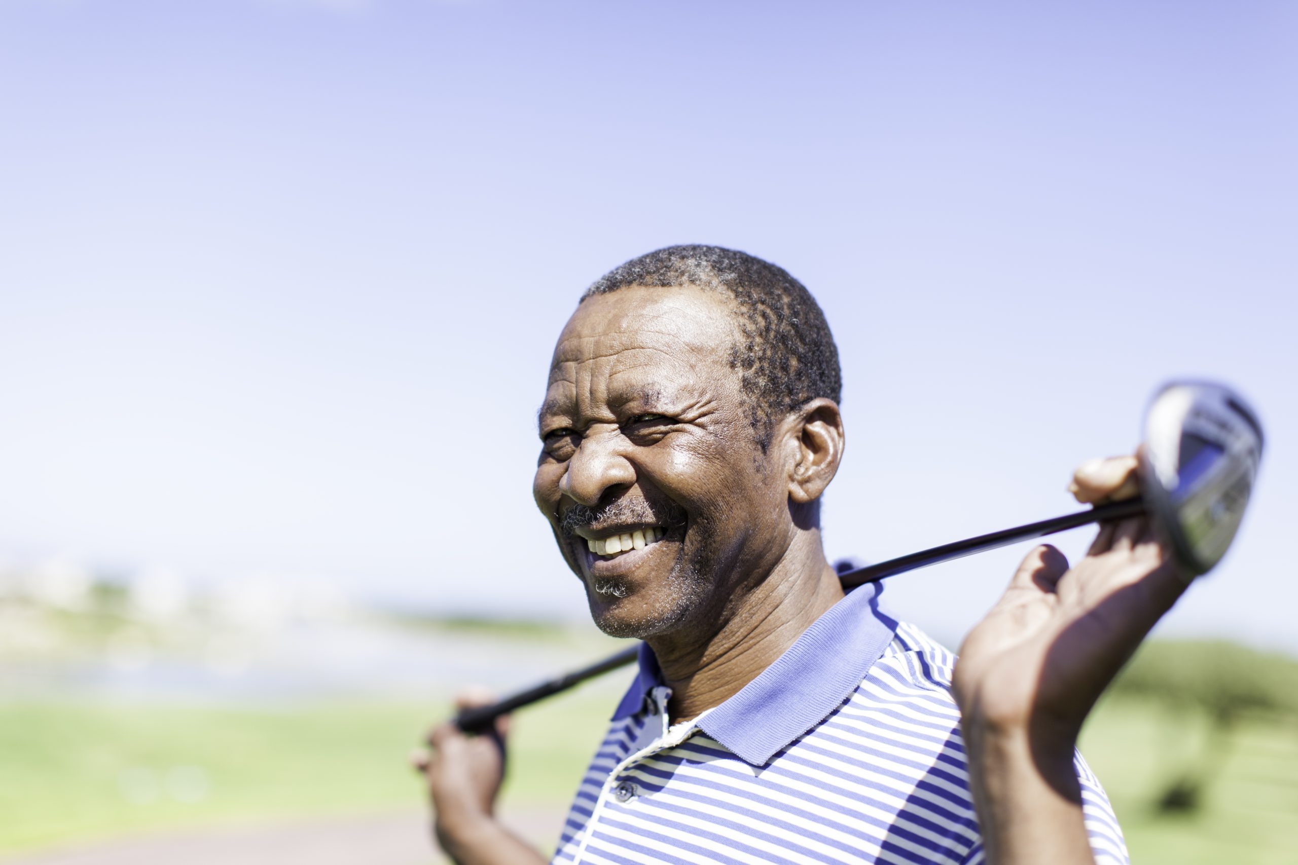 Senior male smiling holding golf club
