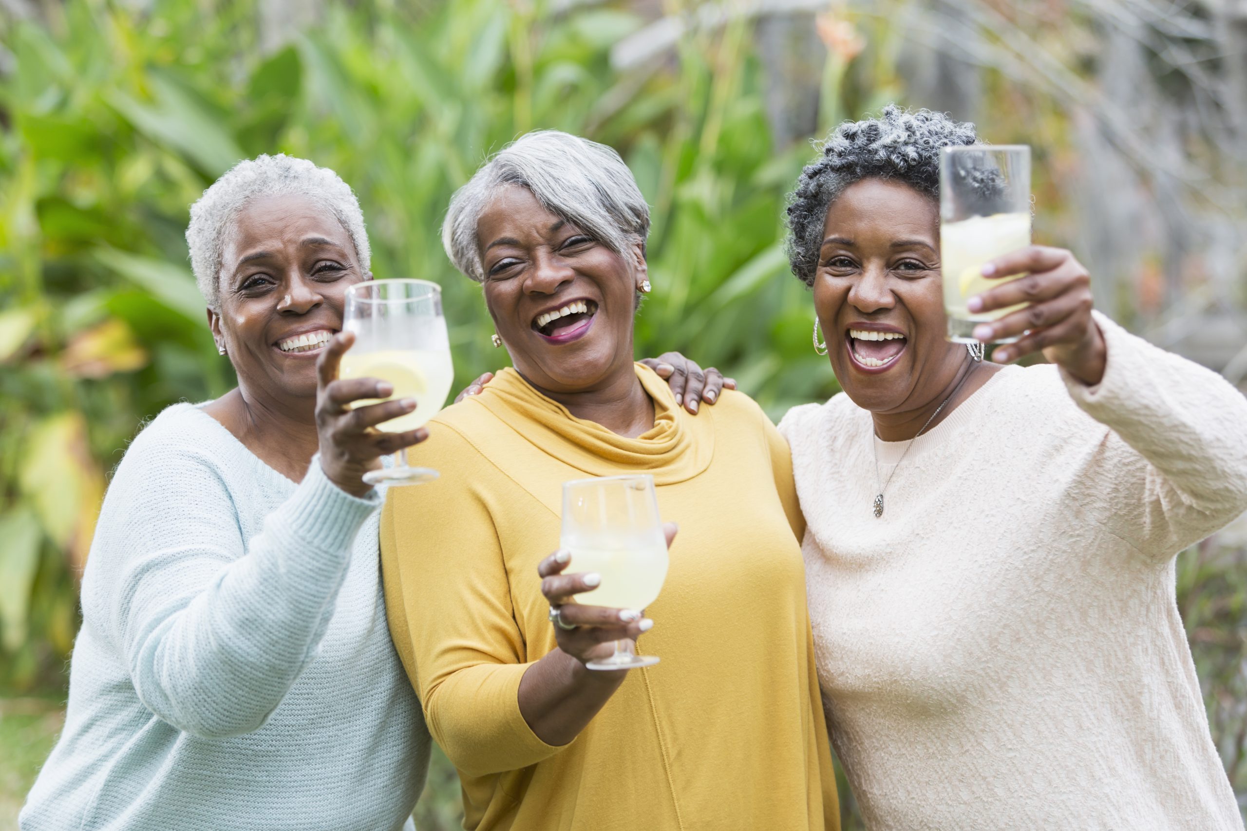 Group of senior women standing outdoors holding glasses of lemonade