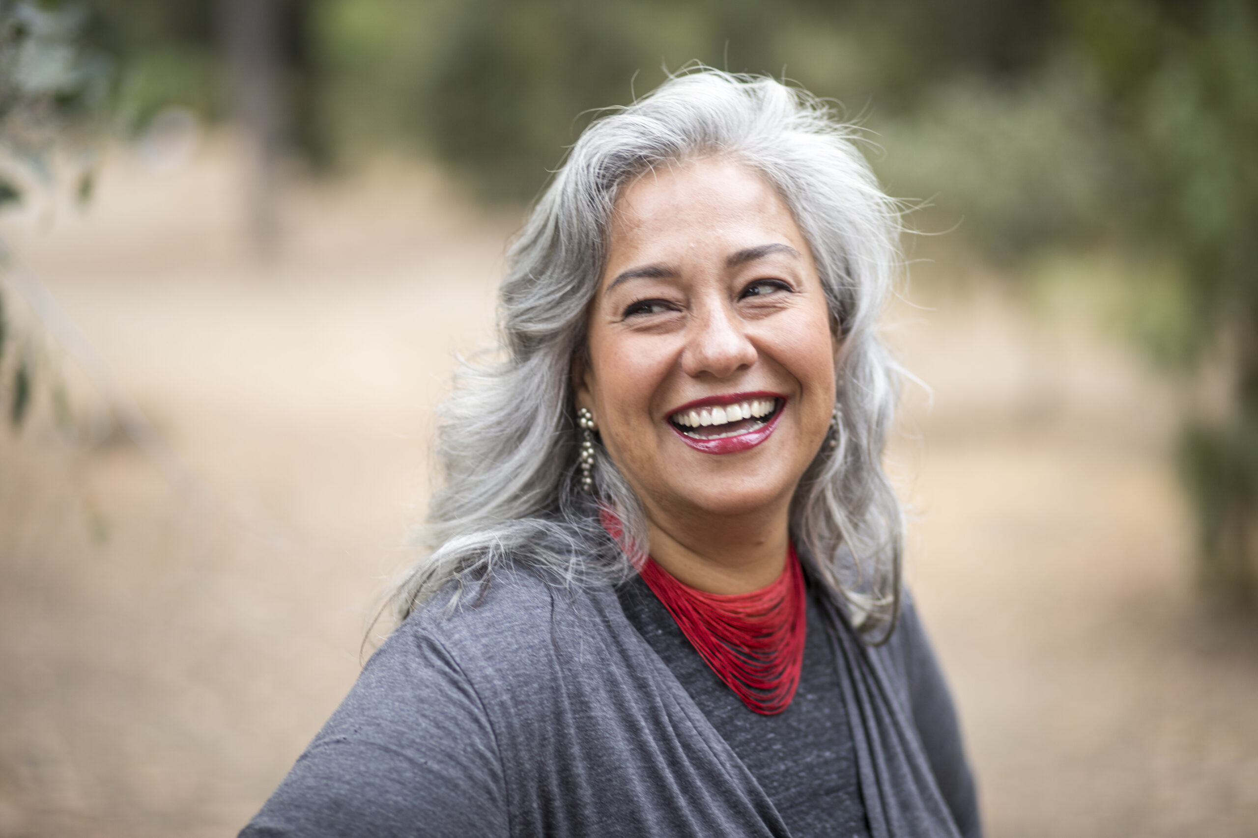 An older woman smiles and laughs brightly while outdoors